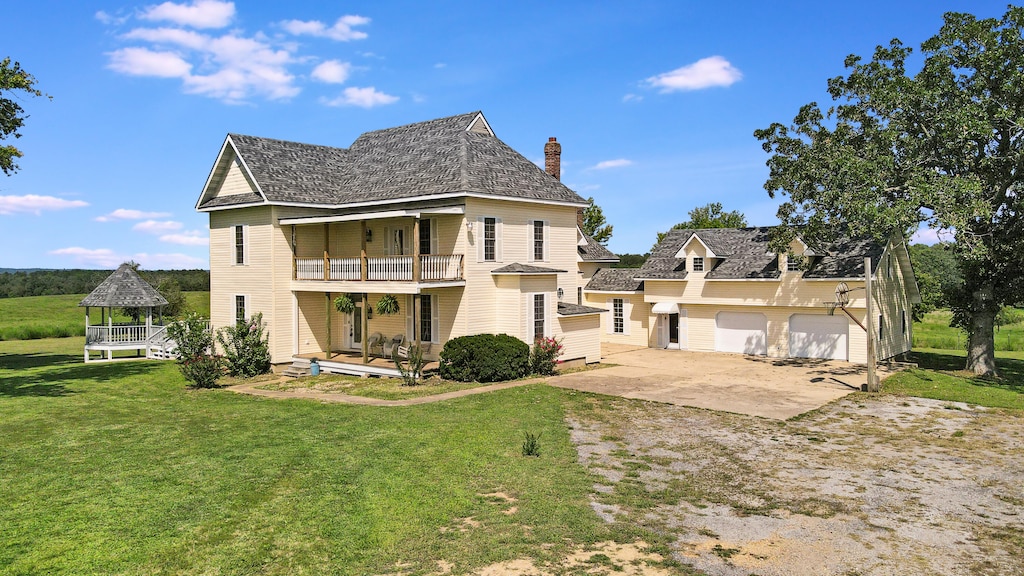 back of house featuring a garage, a yard, and a balcony