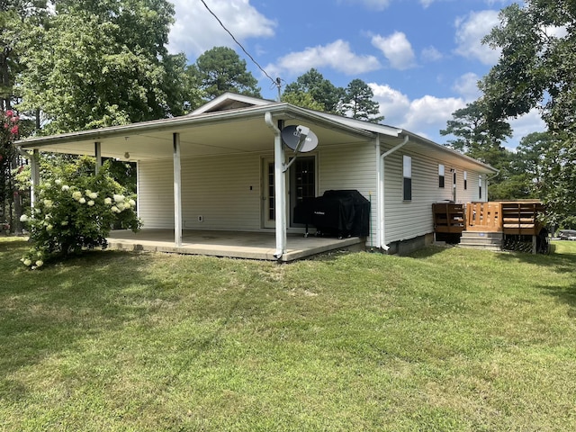 back of property featuring a deck, a lawn, and a patio area