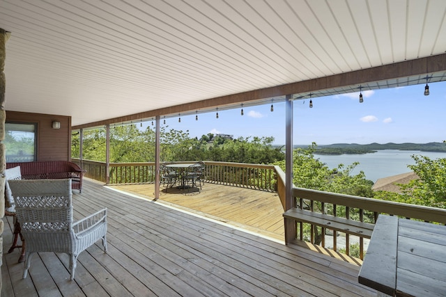 deck with outdoor dining space and a water view