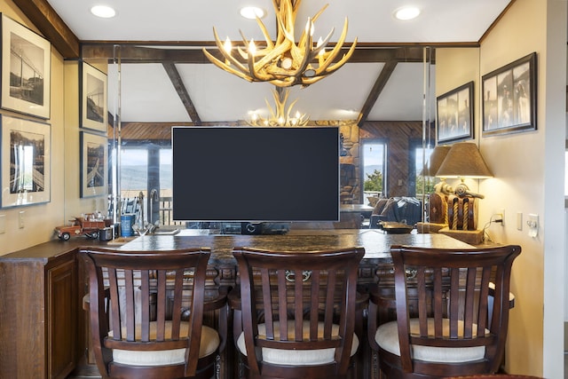 bar with a chandelier, beam ceiling, and indoor wet bar