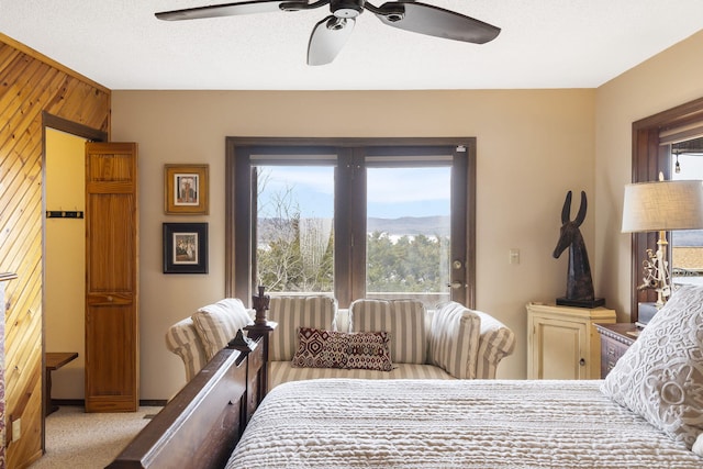 bedroom with carpet floors, multiple windows, wooden walls, and a ceiling fan