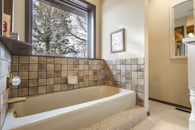 bathroom with a garden tub and baseboards