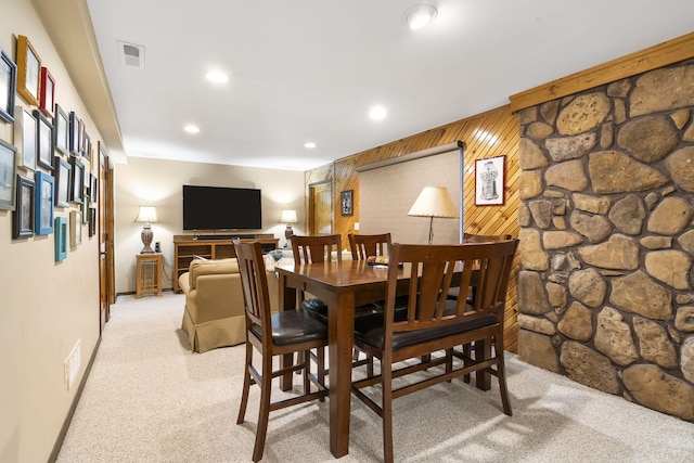 dining space featuring light colored carpet, visible vents, wood walls, and recessed lighting