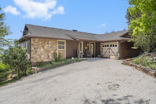 single story home with a garage, stone siding, roof with shingles, and driveway