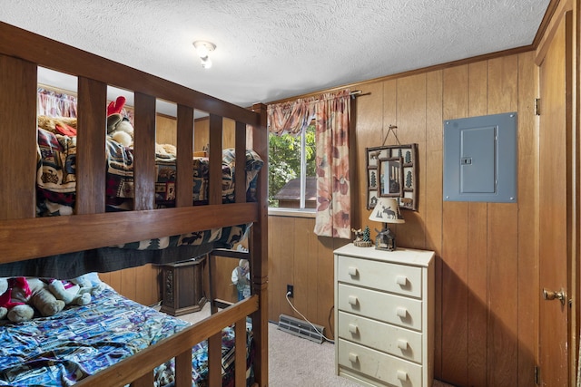 bedroom featuring electric panel, wooden walls, a textured ceiling, and light colored carpet