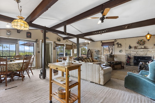 carpeted living room featuring lofted ceiling with beams, ceiling fan, and a stone fireplace