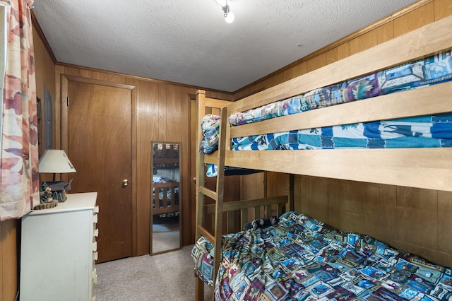 carpeted bedroom with wood walls and a textured ceiling
