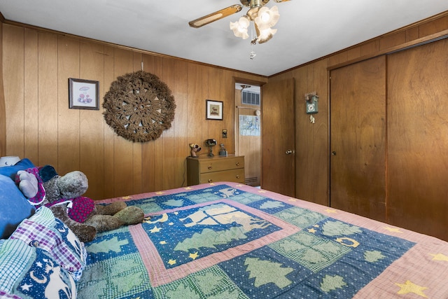 bedroom with ceiling fan, wood walls, and a closet