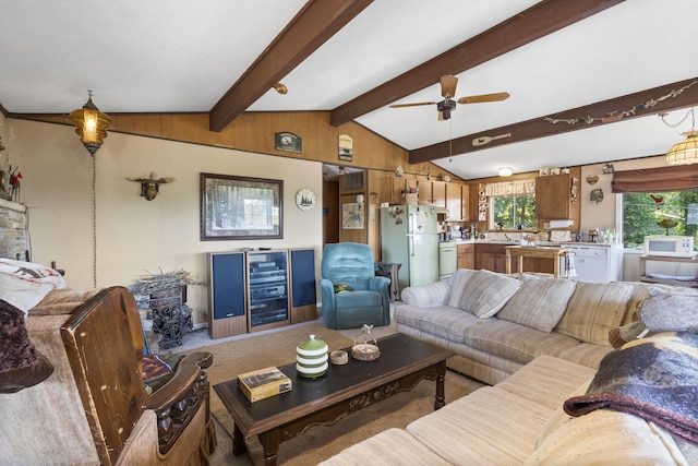 living room with wood walls, lofted ceiling with beams, and ceiling fan