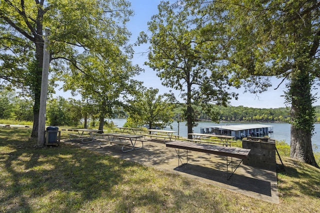 view of property's community with a lawn, a water view, and a dock