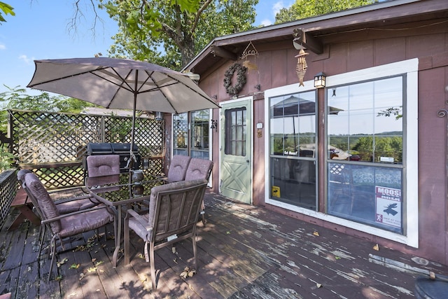 wooden terrace with grilling area, outdoor dining space, and fence