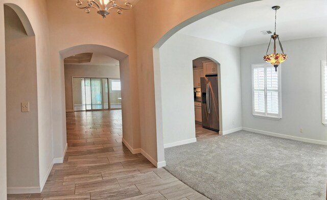 hall featuring light wood finished floors, baseboards, an inviting chandelier, and visible vents