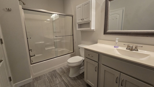 full bathroom featuring vanity, bath / shower combo with glass door, and toilet