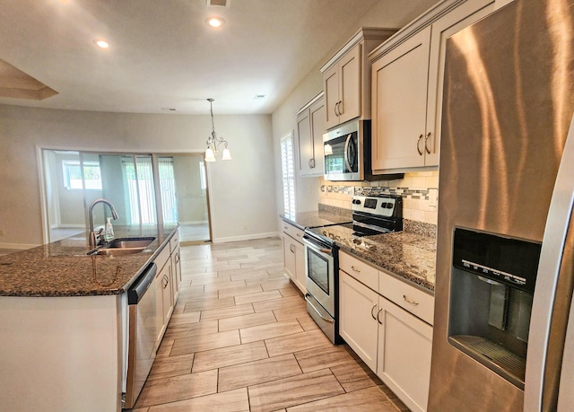 kitchen with a sink, backsplash, baseboards, appliances with stainless steel finishes, and recessed lighting