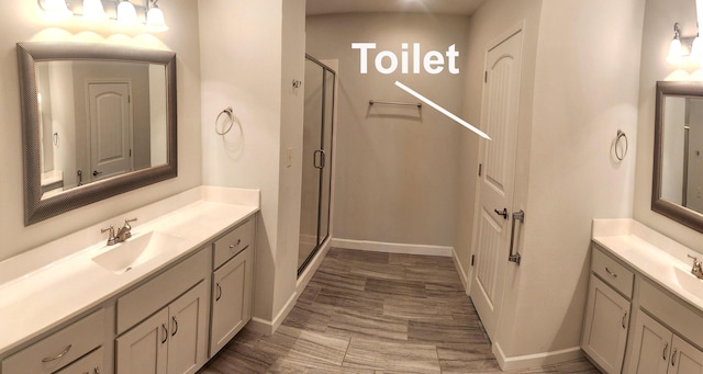 full bath with two vanities, baseboards, a sink, and a shower stall