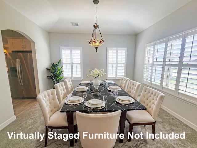 dining space with arched walkways, visible vents, carpet flooring, and baseboards