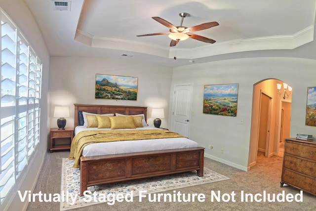carpeted bedroom featuring a tray ceiling, arched walkways, baseboards, visible vents, and crown molding