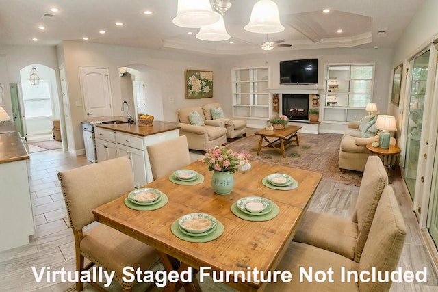 dining space featuring arched walkways, a ceiling fan, a lit fireplace, and recessed lighting