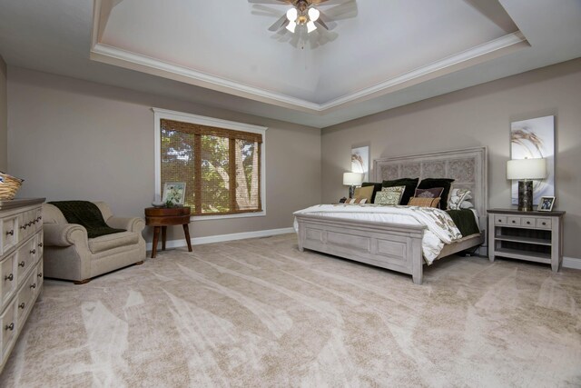 carpeted bedroom with a raised ceiling, baseboards, and ornamental molding