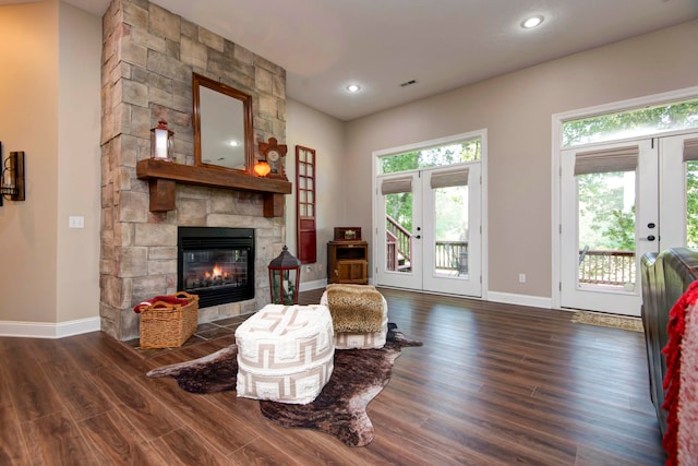 living room with a stone fireplace, french doors, and dark hardwood / wood-style flooring