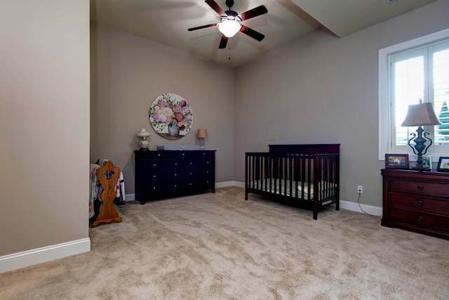 carpeted bedroom with a nursery area and ceiling fan