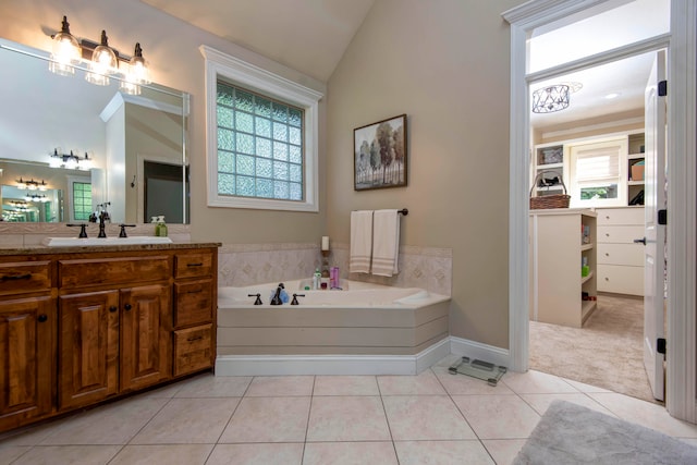 bathroom with lofted ceiling, a tub to relax in, vanity, and tile patterned floors