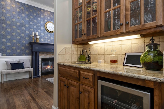bar with wallpapered walls, beverage cooler, a sink, crown molding, and wainscoting