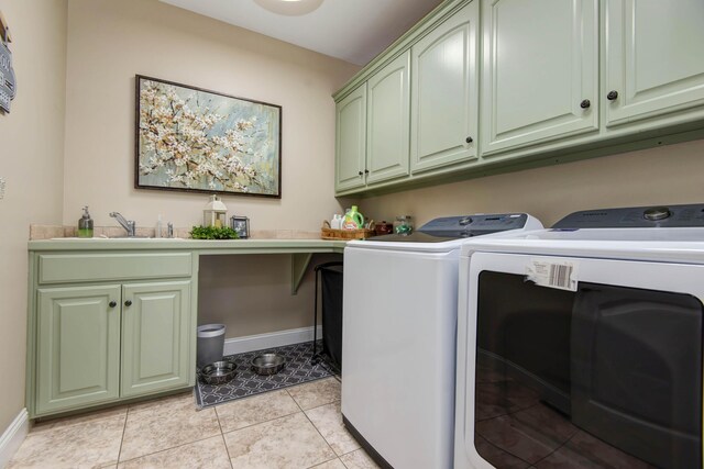 clothes washing area with light tile patterned floors, a sink, washing machine and clothes dryer, baseboards, and cabinet space