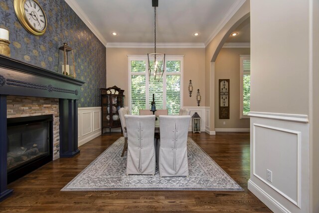 dining room featuring wainscoting, dark wood finished floors, crown molding, and a fireplace