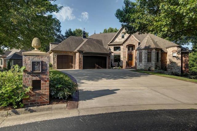 french country style house with an attached garage, driveway, and stone siding