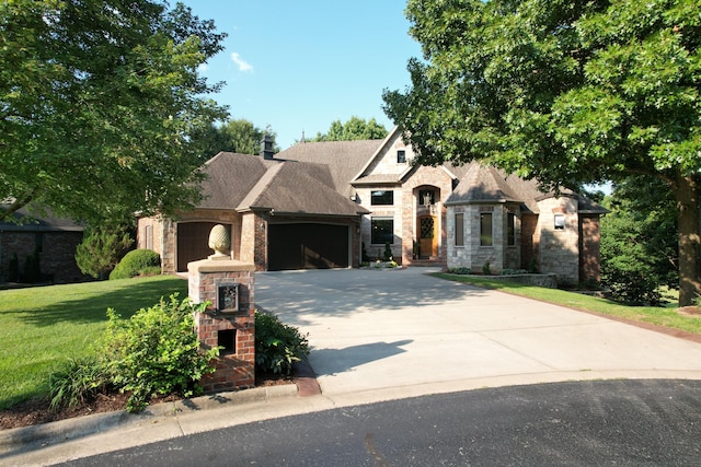 french country home with an attached garage, stone siding, a front yard, and concrete driveway