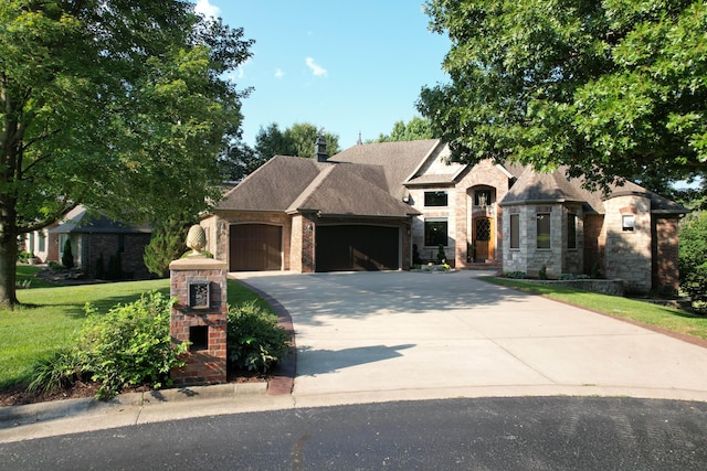 french country inspired facade with concrete driveway, a front lawn, stone siding, a garage, and roof with shingles