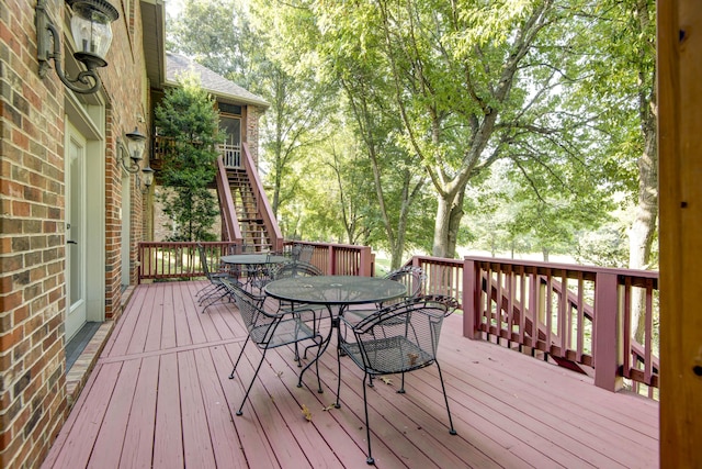 wooden terrace featuring outdoor dining space and stairs