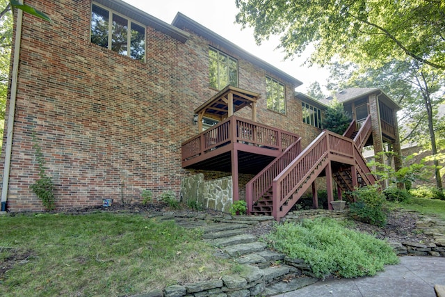 rear view of house with a wooden deck, brick siding, and stairway