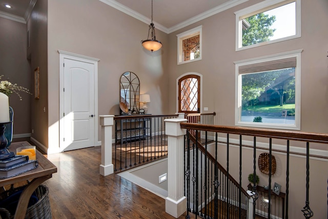 corridor featuring plenty of natural light, ornamental molding, a high ceiling, and hardwood / wood-style flooring