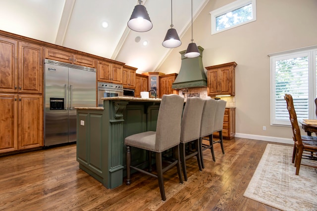 kitchen featuring a breakfast bar area, dark hardwood / wood-style flooring, light stone countertops, an island with sink, and appliances with stainless steel finishes