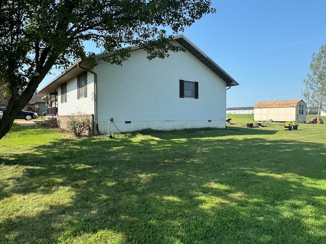 view of side of home with a yard and a storage shed