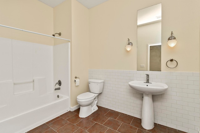 bathroom with tile walls, tile patterned flooring, toilet, and shower / washtub combination