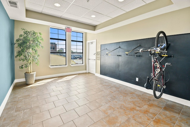 spare room with a raised ceiling, a paneled ceiling, and tile patterned flooring