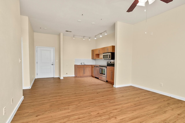 kitchen with tasteful backsplash, appliances with stainless steel finishes, light wood-type flooring, and ceiling fan