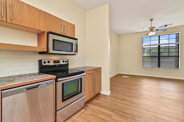 kitchen featuring ceiling fan, stainless steel appliances, light wood-type flooring, and tasteful backsplash