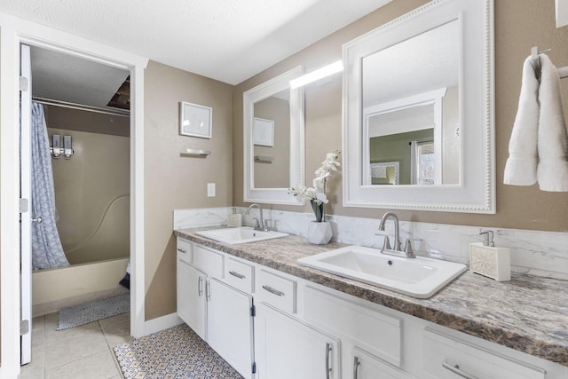 bathroom with tile patterned floors, shower / bath combo with shower curtain, vanity, and a textured ceiling