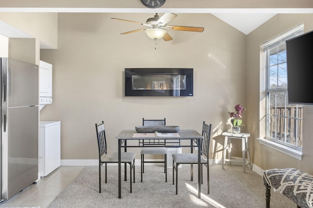 tiled dining room featuring stacked washer and dryer, ceiling fan, and vaulted ceiling