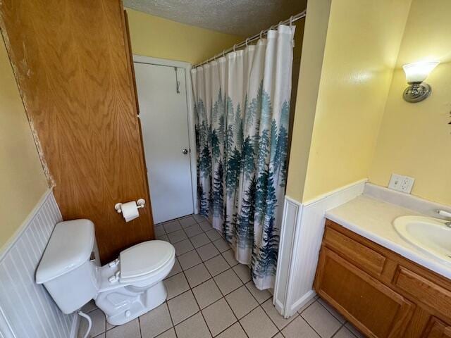 bathroom with vanity, toilet, a textured ceiling, and tile patterned floors