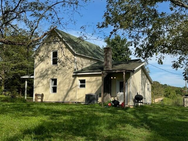 back of property featuring a yard and central AC