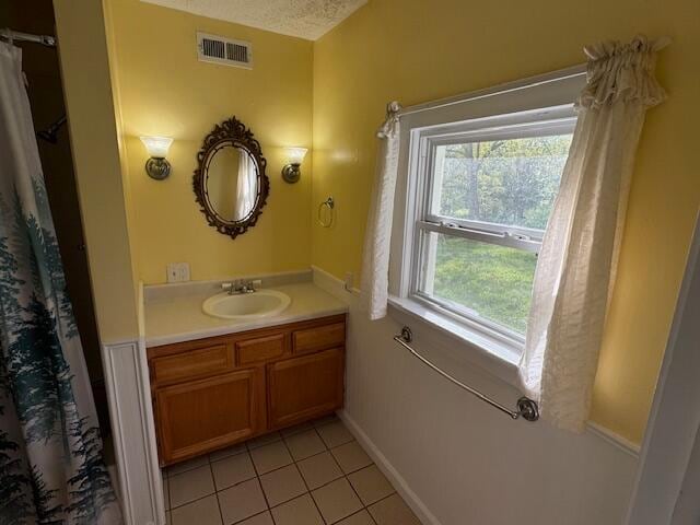 bathroom with tile patterned floors, vanity, and a textured ceiling