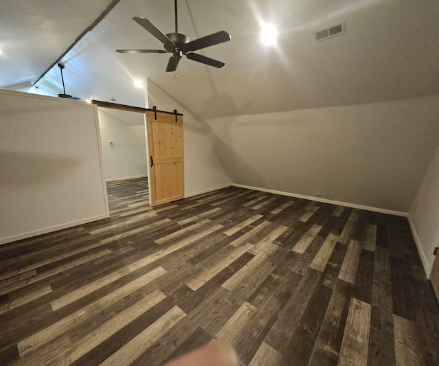 additional living space with a barn door, dark hardwood / wood-style floors, lofted ceiling, and ceiling fan