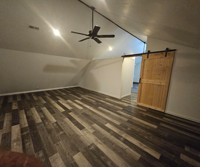 bonus room with ceiling fan, a barn door, vaulted ceiling, and dark hardwood / wood-style floors