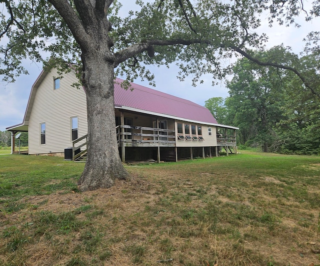 rear view of property with cooling unit, a wooden deck, and a lawn