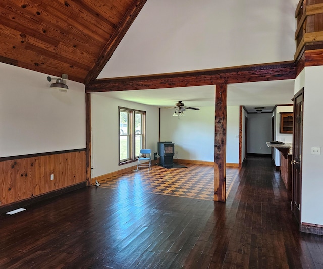 unfurnished living room featuring ceiling fan, a wood stove, dark wood-type flooring, wooden ceiling, and vaulted ceiling